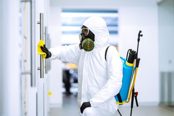 Cleaning and disinfection of office to prevent COVID-19, Man in protective hazmat suit washes office furniture to preventing the spread of coronavirus, pandemic in quarantine city.